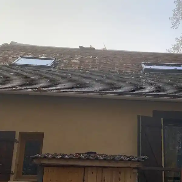 Remplacement de la toiture Loiret - avant : une maison au toit inclin&eacute; avec deux lucarnes, tuiles vieillies et un peu de mousse. Les murs ext&eacute;rieurs sont clairs, avec portes et volets en bois.